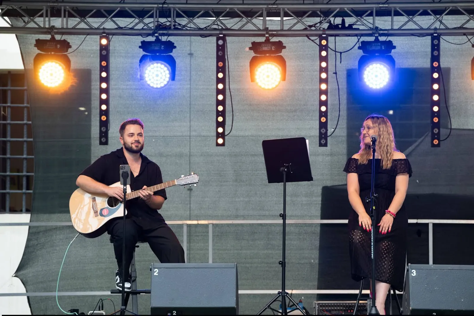 Duet akustyczny na scenie w kolorowym oświetleniu podczas występu